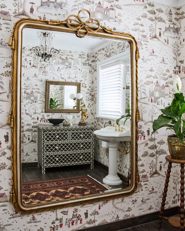 white-based Nina Campbell wallpaper enlivens the powder room, where the vanity is original. Chandelier.