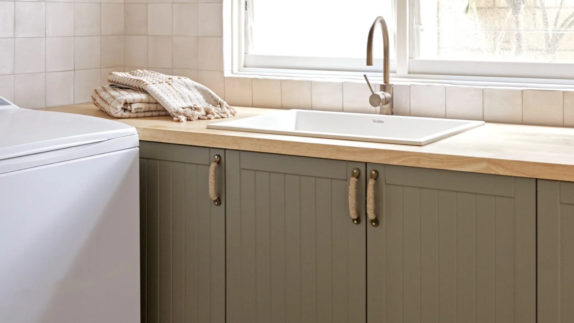 A sage green laundry with plaid-style flooring