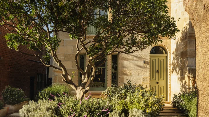 A sandstone Sydney terrace home with a green door and Mediterranean garden
