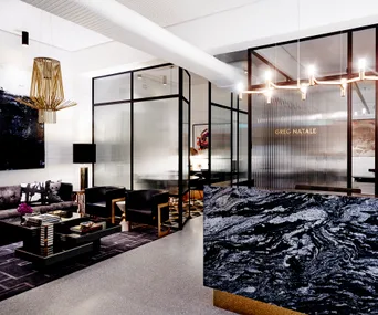 Modern office reception area with marble desk, black and gold decor, and glass partitions; text "Greg Natale" on glass.