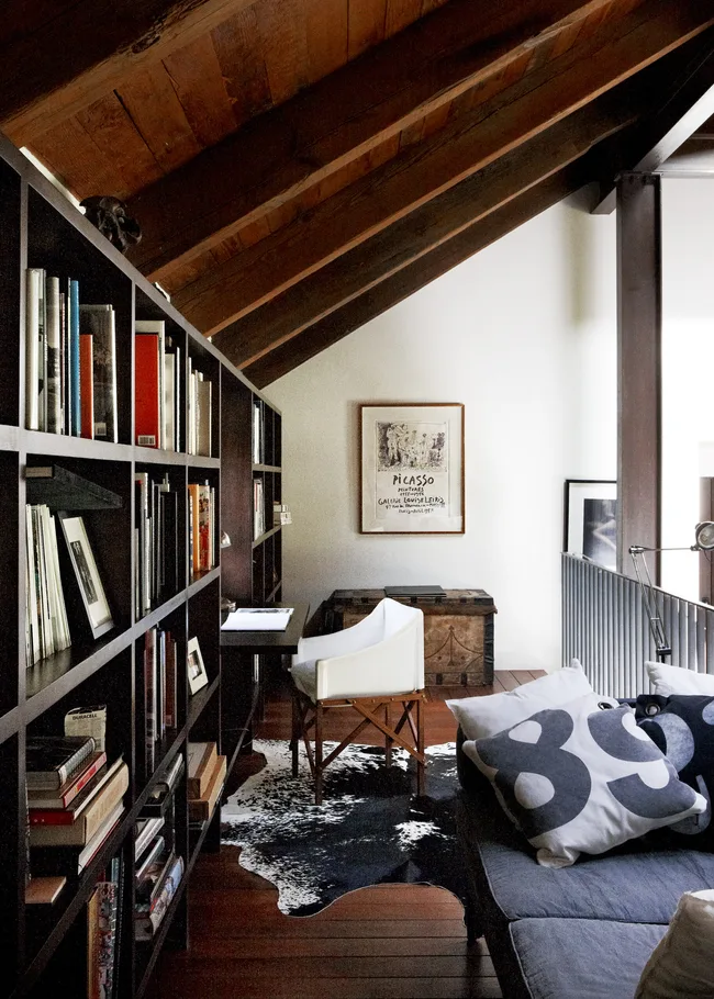 An upstairs study/library with timber flooring and shelves