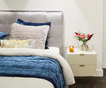 Bed with grey and navy velvet linen and bedside table