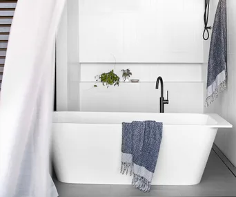 White freestanding bathtub in white coastal bathroom