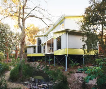 Exterior of an eco-friendly weatherboard home with creek in foreground