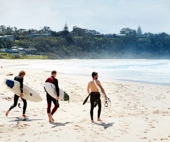 Three surfers on a beach in Mollymook, NSW