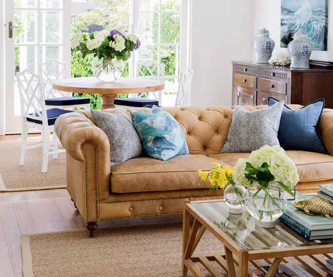 Tan leather chesterfield lounge with blue cushions