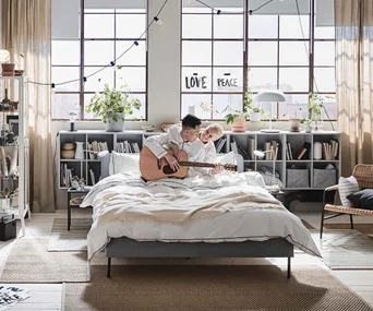 Couple playing guitar in bed with IKEA furniture