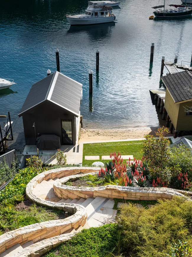 A sloping harbourside garden with a winding bath and boat shed