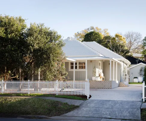 Grey and white cottage with tiled verandah and white picket fence