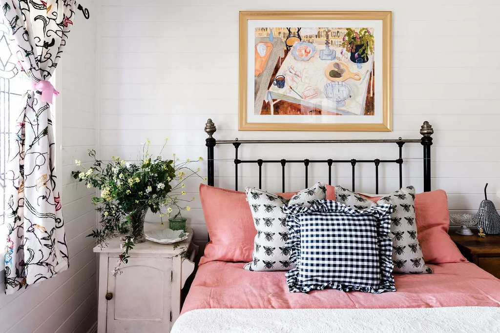 A bedroom with pink bedding and a ruffled cushion