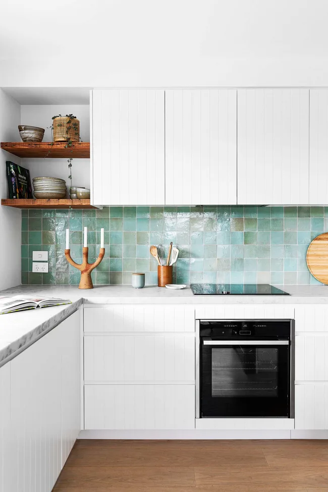 A white kitchen with a blue square-tiled splashback