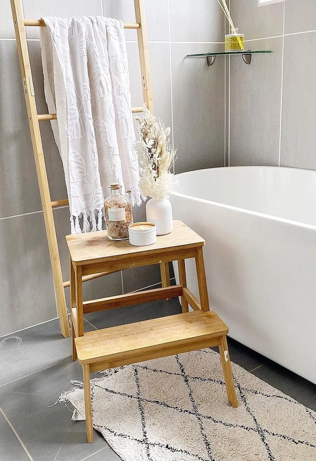 A wooden Kmart stool becomes a handy bathroom storage spot.