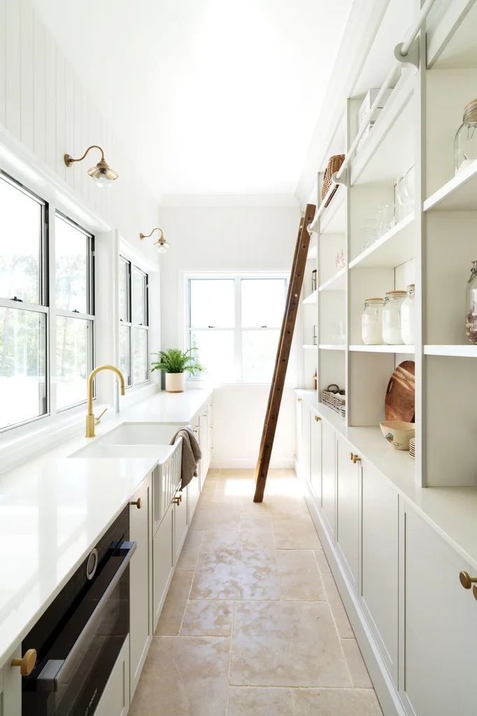 A country-inspired butler's pantry with a farmhouse sink and timber ladder for reaching up to high-level storage