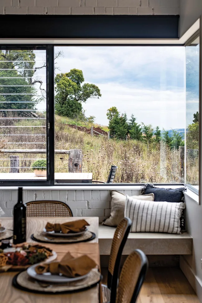 A dining area with a window seat overlooking out to nature