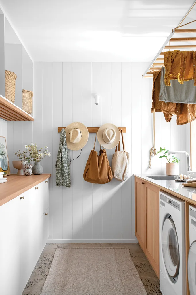 A white and timber laundry space with a built-in airer and plenty of storage