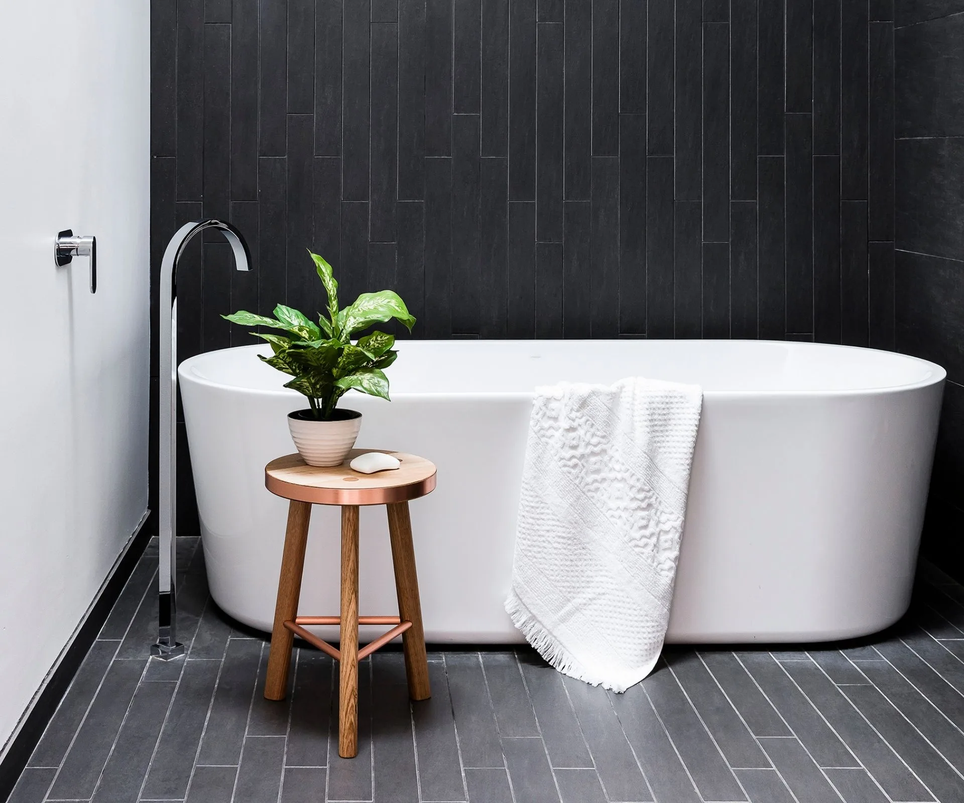 white freestanding bath on black tiled bathroom floor