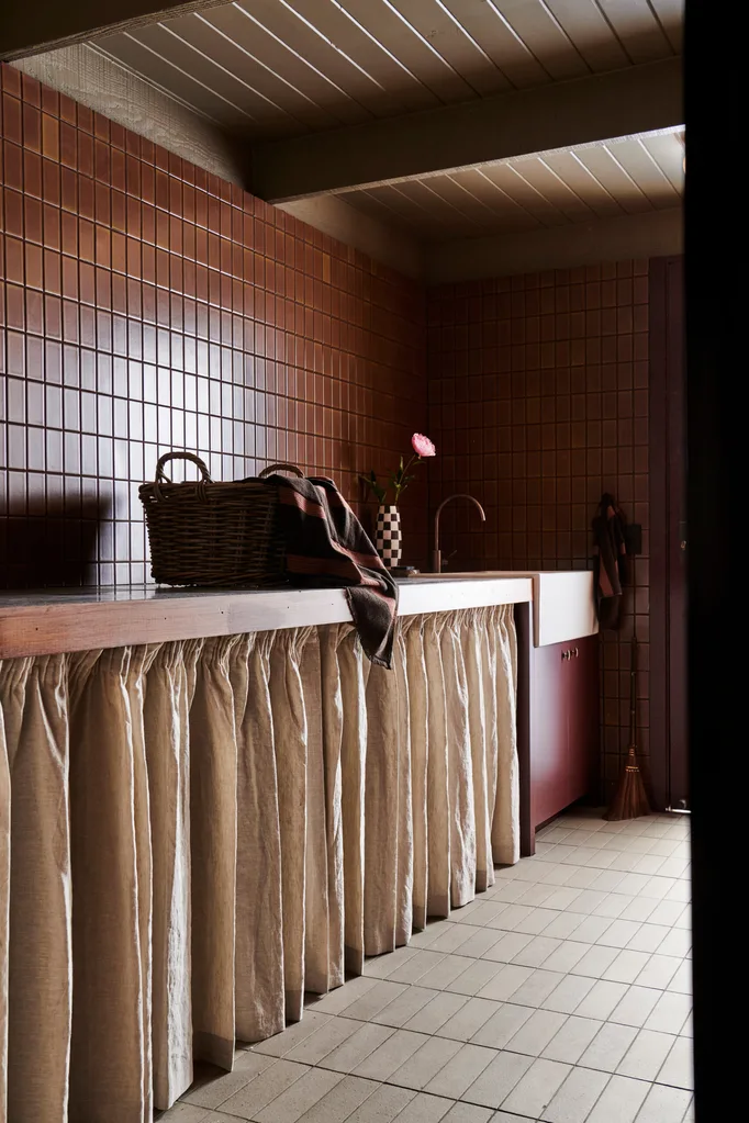 A colour-drenched burgundy laundry with shelving curtains