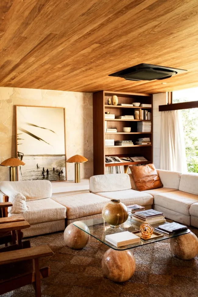 A mid-century-style living room with a neutral toned sofa and brown rug