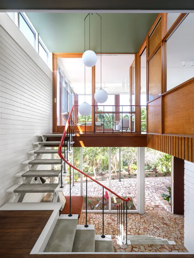 A grand entryway with concrete stairs in a mid-century home